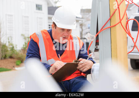 Construction engineer with spinal cord injury taking notes at temporary utility box Stock Photo