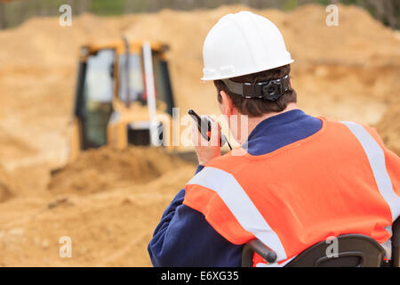 Construction engineer with spinal cord injury on radio to equipment operator Stock Photo