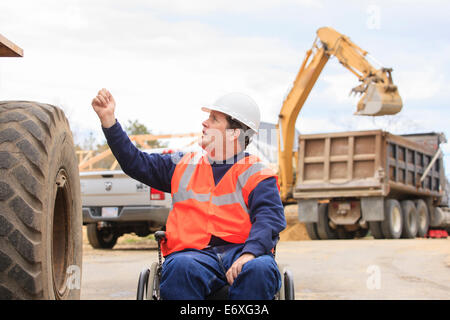 Construction engineer with spinal cord injury talking with front end loader operator Stock Photo