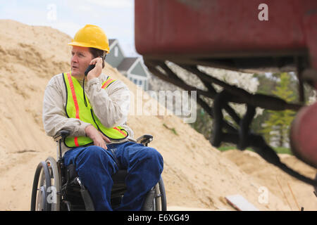 Construction supervisor with Spinal Cord Injury on walkie talkie on construction site Stock Photo