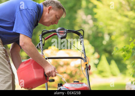 Man with Cerebral Palsy and dyslexia filling his lawn mower with gas Stock Photo