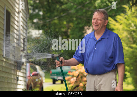 Man with Cerebral Palsy and dyslexia watering his lawn Stock Photo