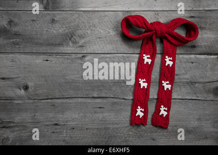 Red knitted bow with deers on wooden background for christmas - greeting card Stock Photo