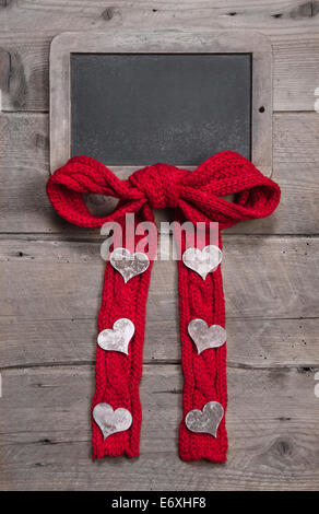 Chalk board for message with red knitted bow and hearts on grey wooden background for valentine's day, mother's day, birthday or Stock Photo