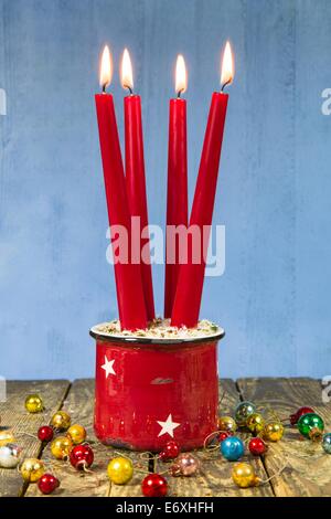 Four red christmas candles on a wooden blue background with old christmas balls for decoration Stock Photo