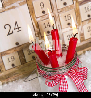 Christmas eve: four red burning candles with a shabby white advent calendar background - classic decoration in country style wit Stock Photo