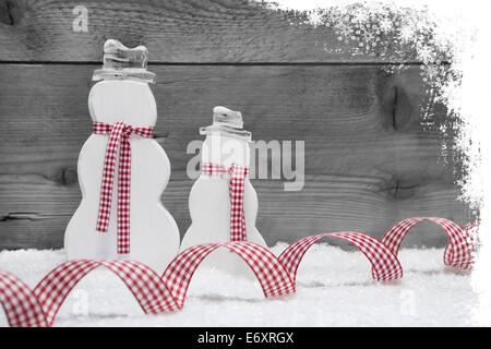 Snowman handmade of wood in red and white on wooden background. Stock Photo