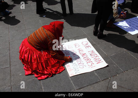 La Paz, Bolivia, 1st September 2014. A woman wearing a red pollera skirt  writes a placard before a march to protest against machismo and violence against women, and to repudiate recent statements made by several candidates during the current election campaign that appear to minimise the problem and discriminate against women. According to a WHO report in January 2013 Bolivia is the country with the highest rate of violence against women in Latin America, there have been 453 cases of femicide since 2006 during the current government. Credit: James Brunker / Alamy Live News Stock Photo