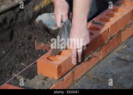 Bricklayer using trowel to tap a brick level Stock Photo
