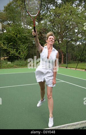 Female tennis player in action on a court stretching to hit the ball Stock Photo