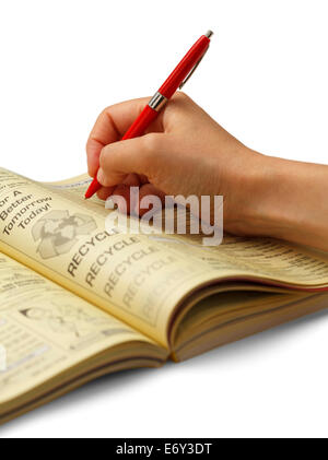 Hand circling phone number with red pen in phone book, isolated on white background. Stock Photo