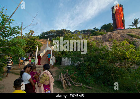 Sri Lankan visitors with small child beneath a buddhist statue near Kirinda, Southern Sri Lanka Stock Photo