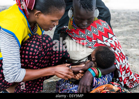 A mobile vaccination team visits a small Turkana village by the Turkana lake and vaccinates the infants and small babies. Stock Photo