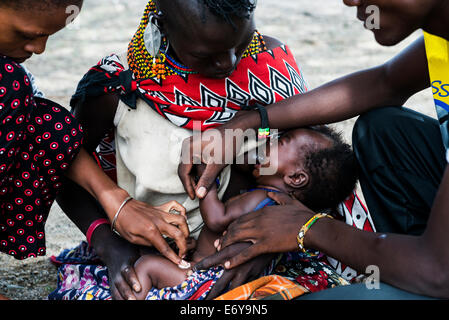 A mobile vaccination team visits a small Turkana village by the Turkana lake and vaccinates the infants and small babies. Stock Photo