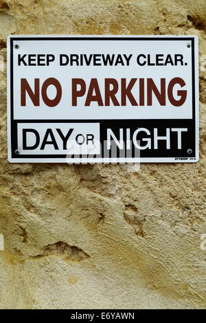 A no parking sign adorns a limestone wall in a residential alley in Fremantle, Western Australia, Australia. Stock Photo