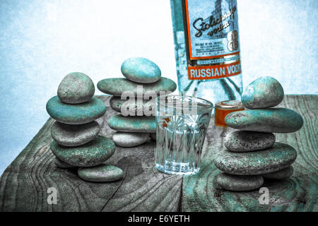A bottle of Russian vodka, cut-glass full of vodka and three stone figures Stock Photo