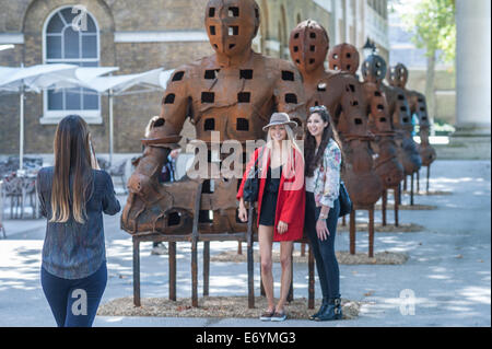 London, UK. 2nd Sept, 2014. visitors pose for pictures next to  Xavier Mascaró's  installation ‘Guardians’. These rusted iron warriors, nearly 10 feet high, are both imposing and placid, and are inspired by medieval armour and ancient Egyptian and Greek art. Xavier Mascaró's first UK solo exhibition will run from 3 September until 5 October at Saatchi Gallery. Credit:  Piero Cruciatti/Alamy Live News Stock Photo