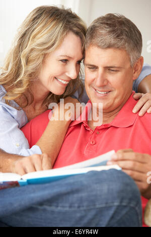 Mid age couple reading book together Stock Photo