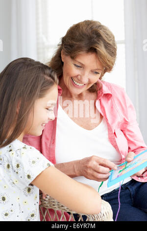 Senior woman doing cross stitch with granddaughter Stock Photo