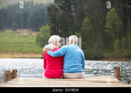 Senior couple sitting on a jetty Stock Photo