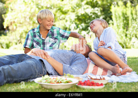 children tormenting father on picnic Stock Photo
