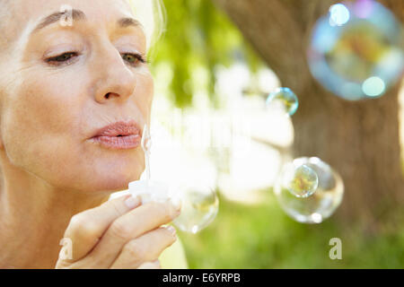 Senior woman blowing bubbles outdoors Stock Photo