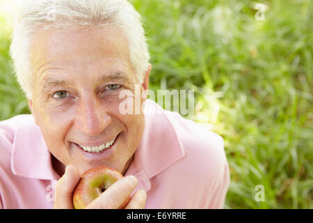 Senior man eating apple outdoors Stock Photo