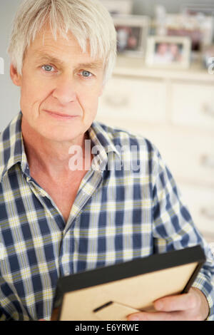 Senior man with photographs at home Stock Photo