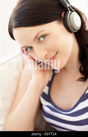 Smiling woman listening to music through wireless in-ear headphones ...