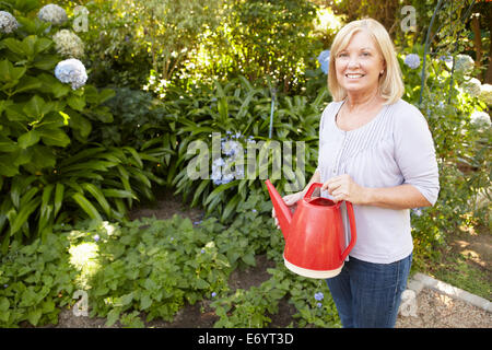 Watering plants in garden, senior woman enjoying outdoor gardening ...