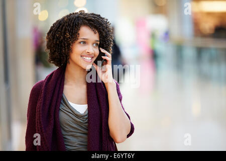 Woman In Shopping Mall Using Mobile Phone Stock Photo