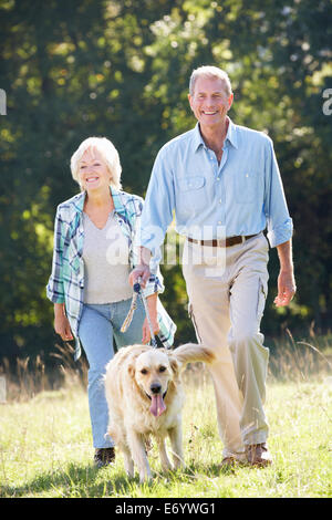 Couple walking their dog in a park Stock Photo - Alamy