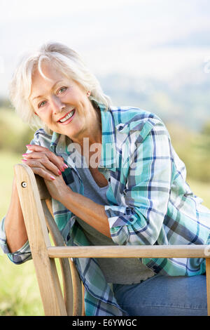 Senior woman sitting outdoors on a chair reading a book Stock Photo - Alamy