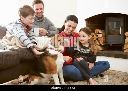 Family Relaxing Indoors And Stroking Pet Dog Stock Photo