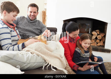 Family Relaxing Indoors Playing Chess And Reading Book Stock Photo