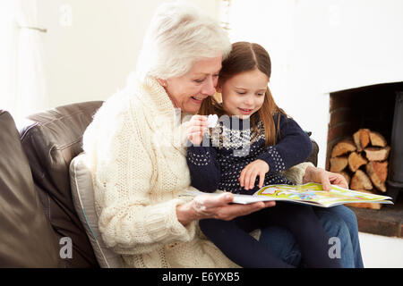 Grandmother And Granddaughter Reading Book At Home Together Stock Photo