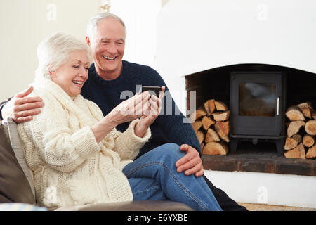 Senior Couple Sitting On Sofa Taking Selfie Stock Photo