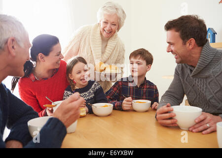 Multi Generation Family Eating Lunch At Kitchen Table Stock Photo