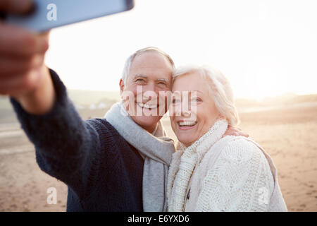 Senior Couple Standing On Beach Taking Selfie Stock Photo