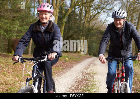 Couple Cycling Along Urban Street Together Stock Photo