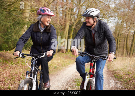 Couple Cycling Along Urban Street Together Stock Photo