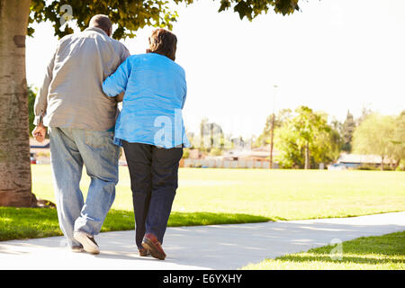 Senior Woman Helping Husband As They Walk In Park Together Stock Photo