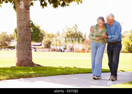 Senior Man Helping Wife As They Walk In Park Together Stock Photo