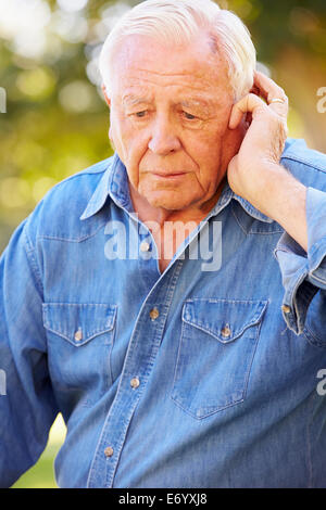 Depressed Senior Man Sitting Outside Stock Photo