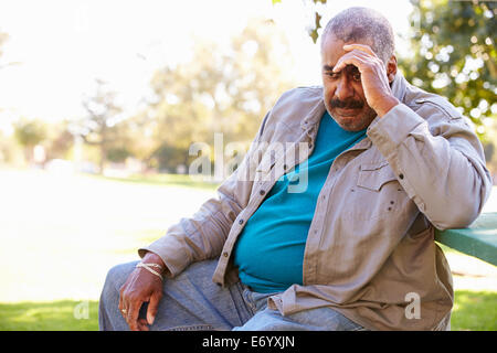 Depressed Senior Man Sitting Outside Stock Photo