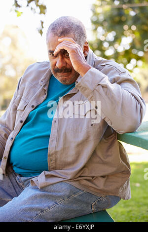 Depressed Senior Man Sitting Outside Stock Photo