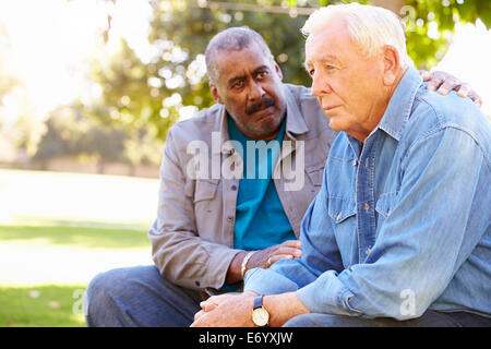 Man Comforting Unhappy Senior Friend Outdoors Stock Photo