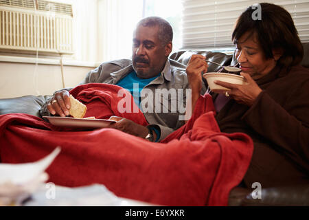 Senior Couple With Poor Diet Keeping Warm Under Blanket Stock Photo