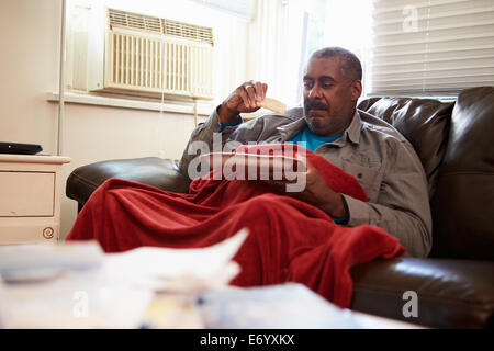 Senior Man With Poor Diet Keeping Warm Under Blanket Stock Photo
