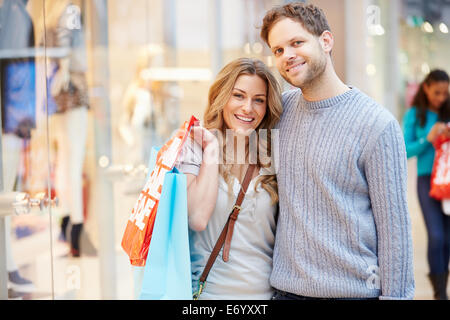 Portrait Of Couple Carrying Bags In Shopping Mall Stock Photo